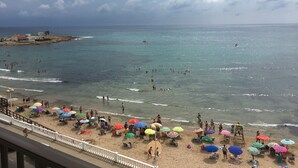 A beach with people swimming and sunbathing, umbrellas, and a lifeguard tower. - SEAVIEWS Apartment - Beachfront Apartment (Torrevieja)