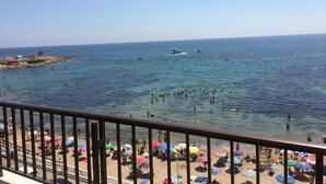 A beach with clear blue water, umbrellas, and people. - SEAVIEWS Apartment - Beachfront Apartment (Torrevieja)