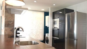 A modern kitchen with a stainless steel refrigerator, built-in oven, and a washing machine. - SEAVIEWS Apartment - Beachfront Apartment (Torrevieja)
