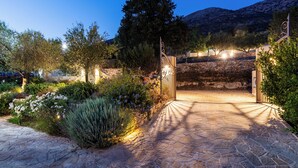 A stone pathway leading to a gate with a mountain backdrop. - Kalliroi - Exquisite Villa Designed Exclusively For Two with Large Private Pool. (Pylaros)