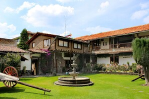 Stroll through a serene courtyard surrounded by lush greenery and a central fountain.