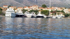 A marina with several yachts docked, surrounded by buildings with red-tiled roofs and palm trees. - Villa Dubrovnik with pool and sea view (Dubrovnik)