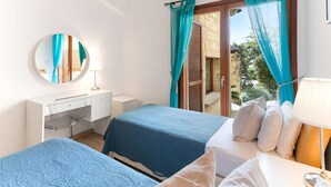 Ein Schlafzimmer mit zwei Betten, einem Schreibtisch, einem Spiegel und einem Fenster mit Vorhängen.