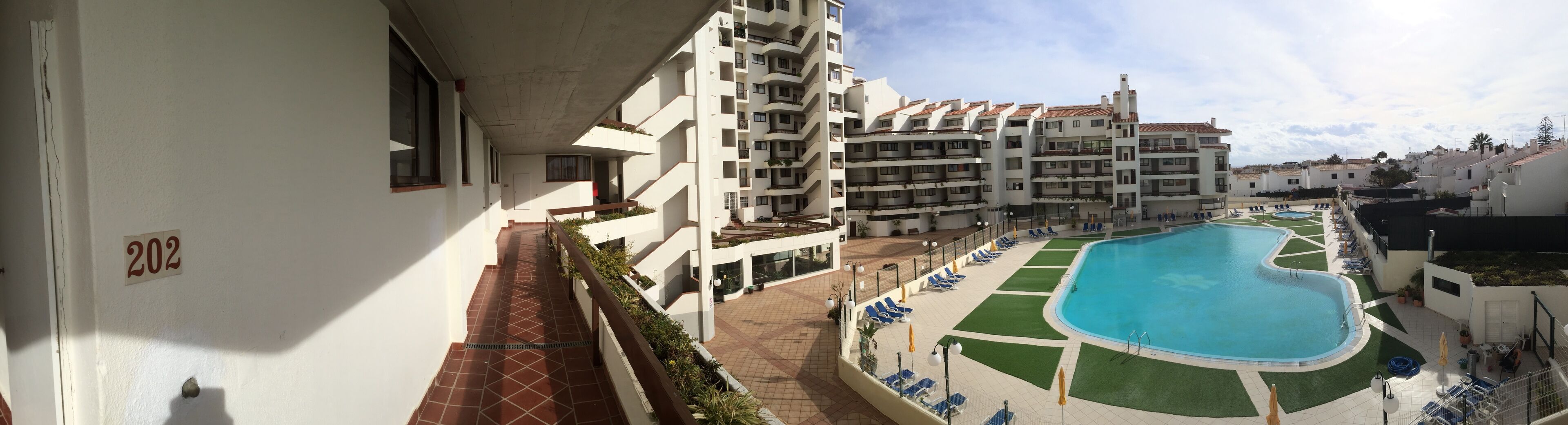 A residential building with a pool area, including a swimming pool and lounge chairs.