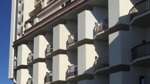 Ein mehrgeschossiges Hotel mit moderner Architektur, mit Balkonen auf jeder Etage und einem markanten Eingang mit einem Schild.