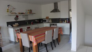 Una cocina con una mesa de comedor, sillas, microondas y estufa.