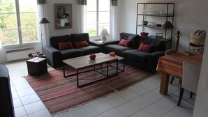 Una sala de estar con dos sofás, una mesa de centro, un televisor y un comedor con una mesa y sillas.