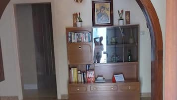 A lobby with a wooden bench, books, a glass display case, and a chandelier.