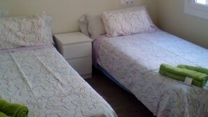 A bedroom with two single beds, each with patterned bedding and pillows. There are two bedside tables, one on each bed. A window is visible on the right side of the room. - Castel apartment Fira (L'Hospitalet de Llobregat)