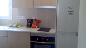 A kitchen with wooden cabinets, a built-in oven, and a refrigerator. - Castel apartment Fira (L'Hospitalet de Llobregat)