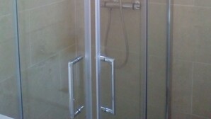 A glass-enclosed shower stall with a handheld showerhead and a wall-mounted faucet. - Castel apartment Fira (L'Hospitalet de Llobregat)