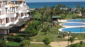 Un resort con piscina, palme e vista sull'oceano.