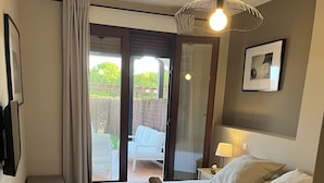 Camera d'albergo con un letto, una piccola panca, un comodino con una lampada e vista all'esterno.