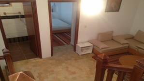Ein kompakter Wohnbereich mit einer Couch, einem kleinen Tisch und einem Bett im Hintergrund.