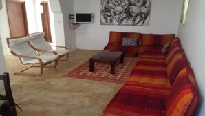 Ein Wohnzimmer mit einer Sofagarnitur, einem Holztisch und zwei weißen Sesseln.
