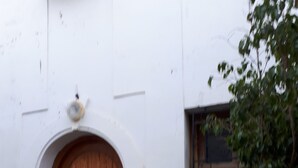 Ein weißes Gebäude mit einer Holztür und einem kleinen Fenster.