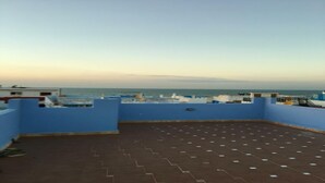 Eine Dachterrasse mit Blick auf das Meer, blauen Wänden und einem gefliesten Boden.