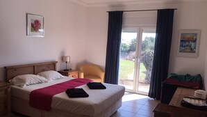 Ein Hotelzimmer mit Bett, Sessel, Schreibtisch und Blick durch eine Glastür.