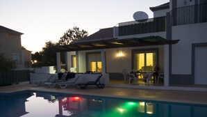 Ein Swimmingpool mit Liegestühlen und einer Terrasse mit Tisch und Stühlen.