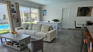 Una sala de estar moderna con sofá, mesa de centro y comedor con mesa y sillas.