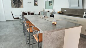 Una cocina moderna con una isla grande, taburetes de bar y un comedor.
