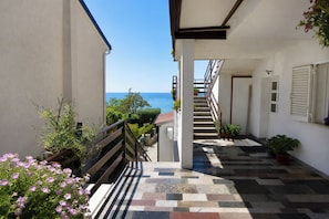 A corridor with a view of the sea, a staircase, and potted plants.