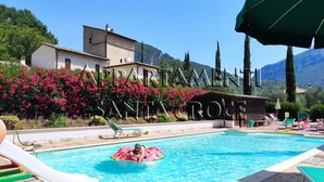 Una piscina con tobogán, sillas de descanso y un edificio con el letrero 'MARIBAR SANTINO ROCE'.