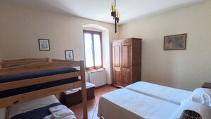 Un dormitorio con literas, un armario de madera, un radiador y una ventana con cortinas.