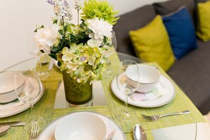 Una tavola imbandita con piatti, bicchieri, posate, un vaso con fiori e una tovaglia verde.