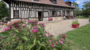 A traditional half-timbered house with a stone foundation, a tiled roof, and a gravel driveway. - A pastoral setting within reach of seaside (12-25 kms) - Sleeps 6-8 (Manneville-La-Raoult)