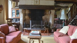 A cozy living room with a fireplace, two sofas, a coffee table with books, and a staircase leading upstairs. - A pastoral setting within reach of seaside (12-25 kms) - Sleeps 6-8 (Manneville-La-Raoult)