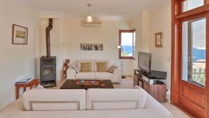 Un salon comprenant un canapé, une table basse, une cheminée, un téléviseur et une vue sur la mer par une fenêtre.
