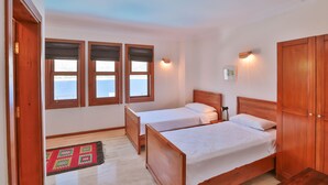 Une chambre avec deux lits simples, une armoire en bois et une fenêtre donnant sur un paysage agréable.