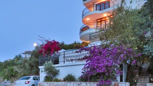 Un immeuble à plusieurs étages, doté de balcons, de murs en pierre et de plantes en fleurs.