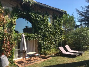 Une terrasse avec une table et des chaises, un transat et un espace salon abrité.