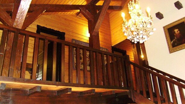 Una escalera de madera con un candelabro y un retrato enmarcado en la pared.