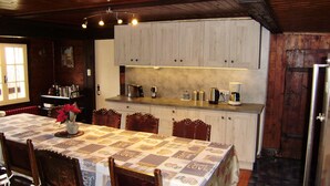 Una cocina acogedora con armarios de madera, una encimera con cafeteras y una mesa de comedor con sillas.