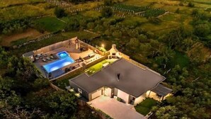 Una casa amb piscina, mobiliari exterior i un jardí gran.
