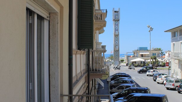 Un balcón con vista a coches aparcados y una calle.