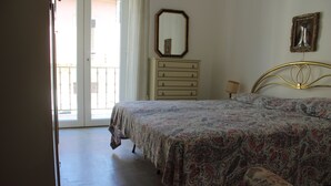 Un dormitorio con cama, cómoda, espejo y ventana.