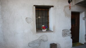 Un bâtiment à l’aspect rustique, avec une petite fenêtre, une porte en bois et un marchepied en pierre.