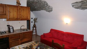 Une cuisine avec des meubles en bois, un canapé rouge et un mur en pierre.