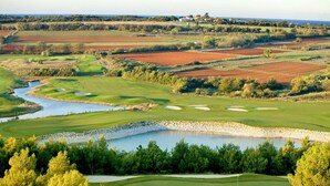 A golf course with a lake, sand bunkers, and a distant view of houses. - Umag Savudrija Vacation Home, near the beach, balcony, Wi-Fi (Bašanija)