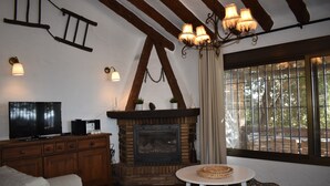 Un salon chaleureux avec une cheminée, des poutres en bois et un téléviseur.