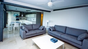 A modern living room with two grey sofas, a white coffee table, and a ceiling fan.