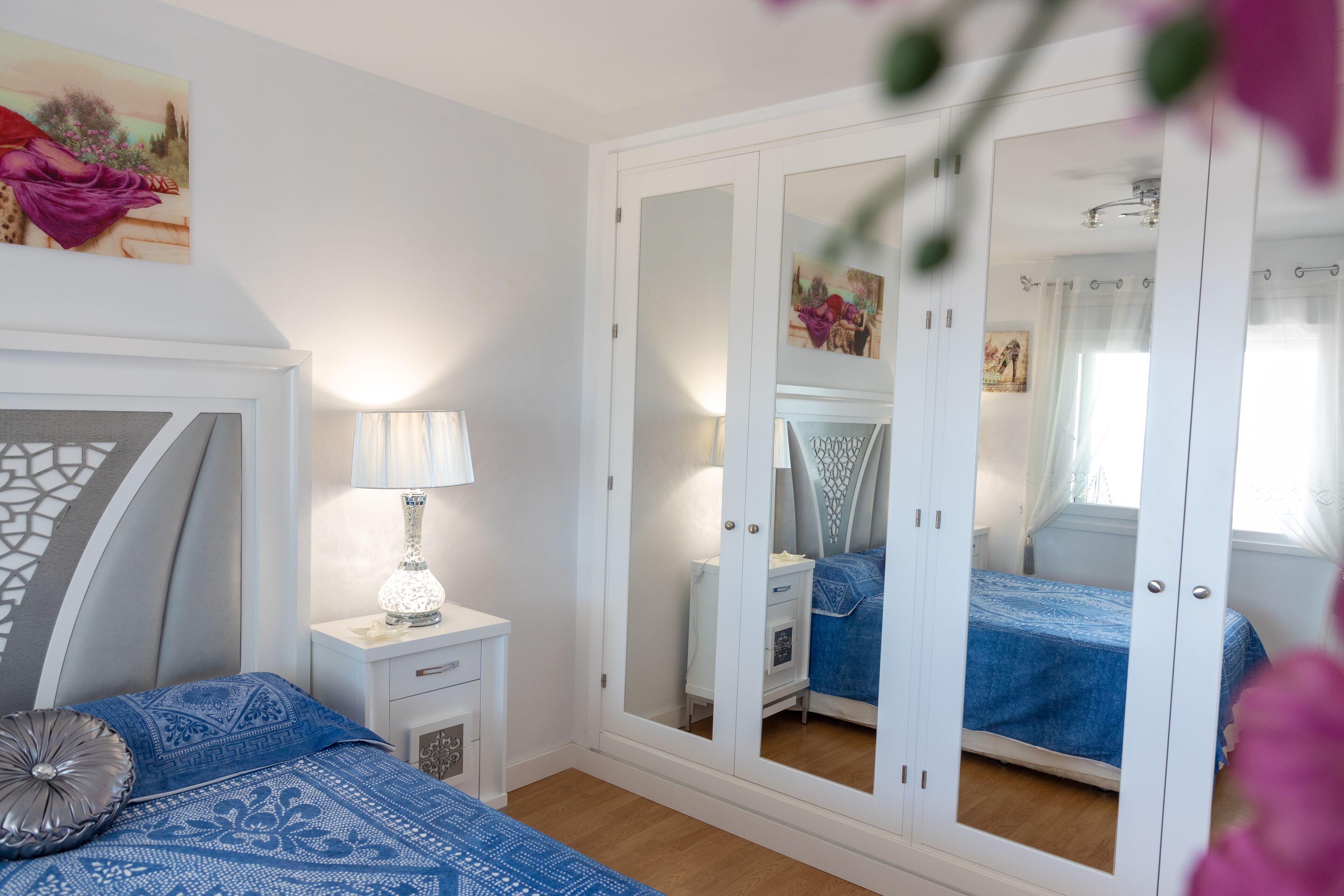 A bedroom with a bed, nightstand, lamp, and wardrobe.