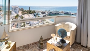 A balcony with a view of the sea, a chair, a globe, and a small table with decorative items. - Nice apartment in the marina (Estepona Malaga)