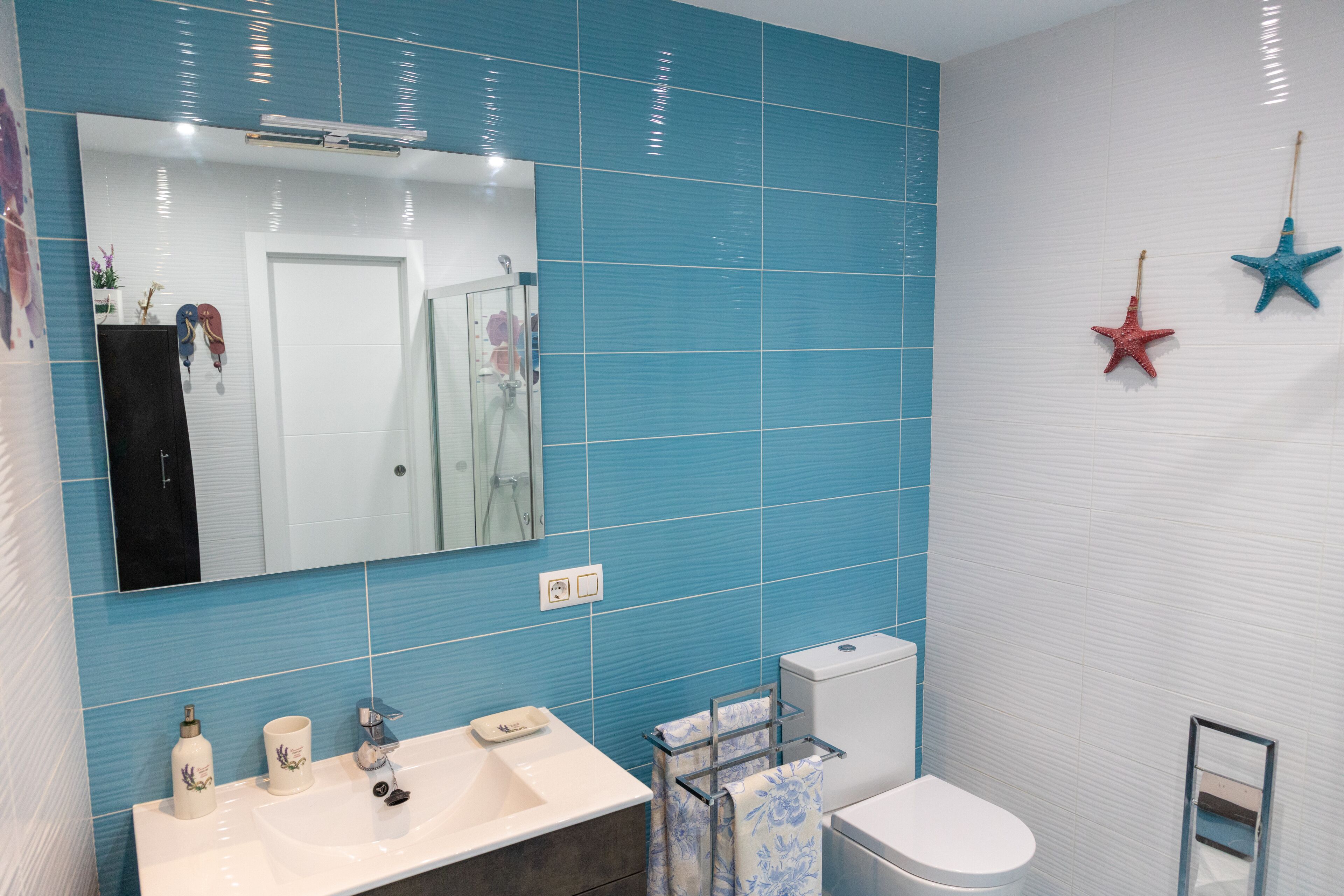 Un baño con un lavamanos blanco, un inodoro y un espejo.