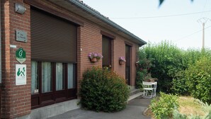 A brick building with a closed garage door, a sign indicating a location, and a small outdoor seating area with a table and chairs.