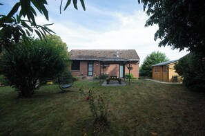 A residential property with a brick house, a covered patio, and a lawn.